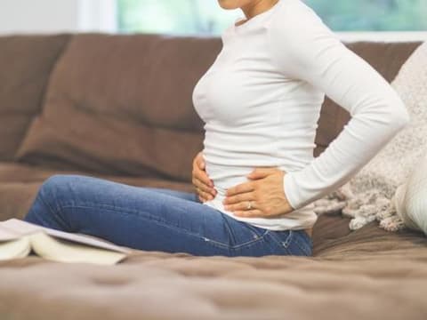 Frau hält sich die Hände vor dem Bauch.