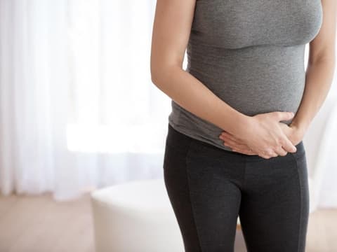 Schwangere Frau hält sich die Hände vor dem Bauch.