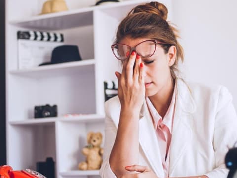 Frau schiebt ihre Brille hoch, scheint erschöpft zu sein.