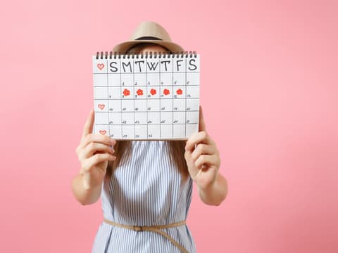 Frau mit Menstruationskalender in der Hand