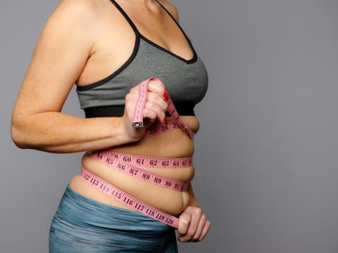Frau mit Maßband um den Bauch