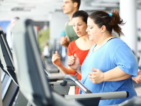 übergewichtige Frau läuft auf Laufband