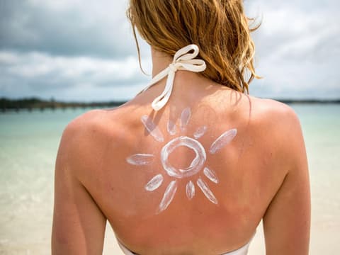 Frau mit Sonnencreme auf dem Rücken