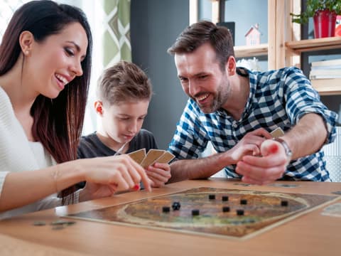 Familie sitzt am Tisch und spielt ein Brettspielt