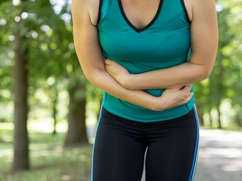 Frau beim Sport mit Bauchschmerzen