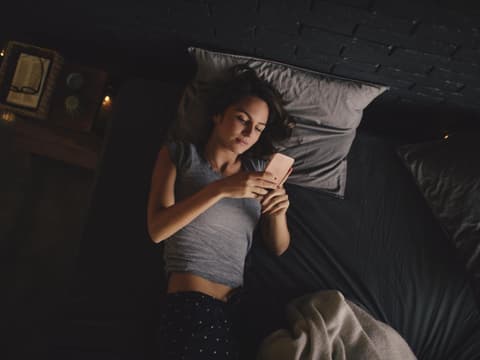 Frau mit Smartphone im Bett