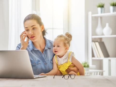 Frau mit Kleinkind am Schreibtisch arbeitend