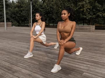 Zwei Frauen machen Ausfallschritte Zwei Frauen machen Ausfallschritte