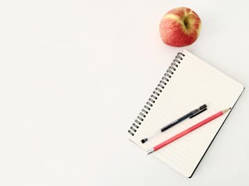 Notizblock mit Stiften und einem Apfel Notizblock mit Stiften und einem Apfel
