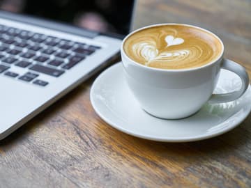 Milchkaffee neben Laptop Milchkaffee neben Laptop