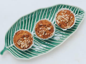 Drei Haferflockenmuffins auf einem blattförmigen Teller Drei Haferflockenmuffins auf einem blattförmigen Teller