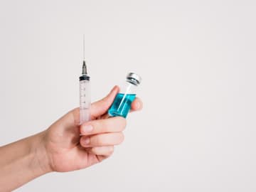Hand hält Spritze und Impfstoff-Fläschchen Hand hält Spritze und Impfstoff-Fläschchen