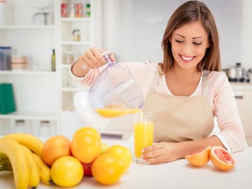 Frau gießt Orangensaft ins Glas Frau gießt Orangensaft ins Glas