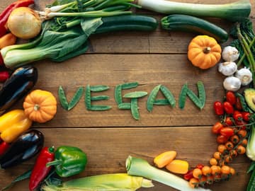 Kreis aus Gemüse um einen Vegan-Schriftzug aus Erbsenschoten Kreis aus Gemüse um einen Vegan-Schriftzug aus Erbsenschoten