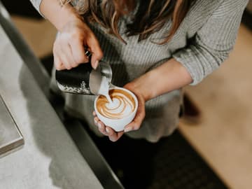 Frau bereitet Milchkaffee zu Frau bereitet Milchkaffee zu