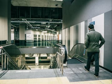 Mann geht auf Rolltreppe zu Mann geht auf Rolltreppe zu