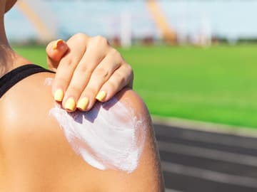 Sonnencreme im Frühling Frau trägt Sonnencreme auf