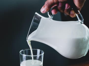 Milch als Retinol-Lieferant Mann gießt frische Milch in Glaskanne