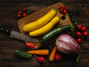 Gelbe Zucchini sind gesund Gelbe Zucchini auf Schneidebrett mit anderen Gemüsesorten