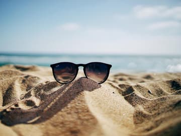 Die besten nachhaltigen Sonnenbrillen Sonnenbrille im Sand am Strand