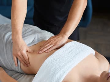 Gezielt kleine Verspannungen lösen Frau erhält krampflösende Bauchmassage