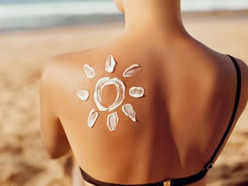 Woman has painted sun on shoulder with sunscreen