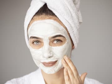 Gesichtsmaske für Feuchtigkeit junge Frau trägt Creme-Maske auf Gesicht auf