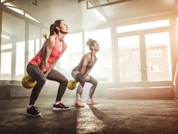 Kettlebell Swings für Rücken und Rumpf Zwei Frauen üben Kettlebell Swings