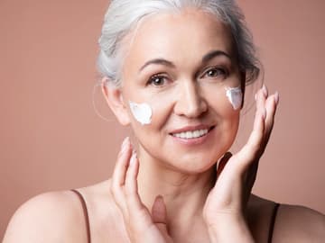 CC Cream für reife Haut Frau im mittleren Altern cremt Gesicht ein