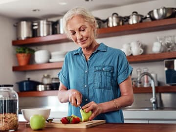 Gesund snacken auch mit fortschreitendem Alter Frau bereitet Snack in Küche zu