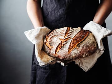 Sauerteigbrot ist lange haltbar Bäckerin hält frisches Sauerteigbrot in den Händen