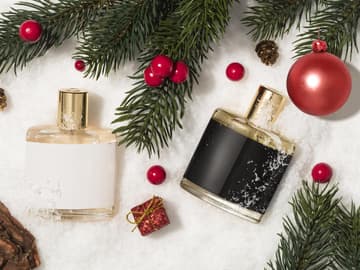 Winterparfums riechen wohlig-warm Parfumflakons auf Schnee mit Zweigen und Weihnachtskugeln