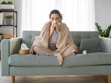 Frau mit Erkältung sitzt auf Couch
