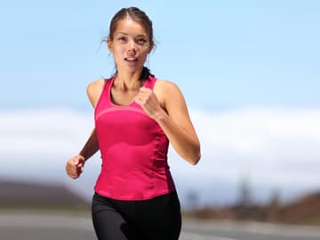 Frau mit rotem Top joggt in der Natur Frau joggt draußen