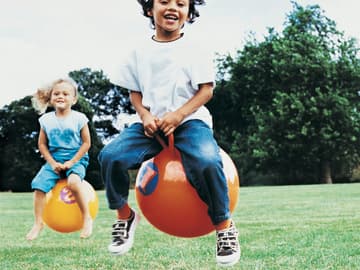Kinder auf einem Hüpfball Kind mit Hüpfball