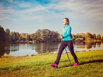 Frau beim Nordic Walking am Flussufer Nordic Walking
