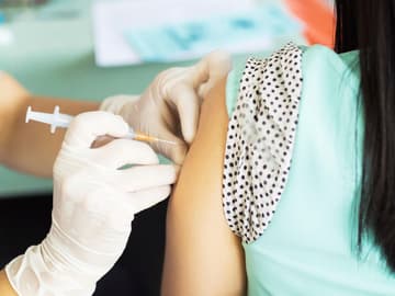 Arzt sticht Spritze in den Arm einer Patientin Grippeimpfung