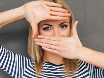 Frau-mit-Händen-vorm-Gesicht Diese Frau verdeckt mit ihren Händen alles, außer ihre Augen.