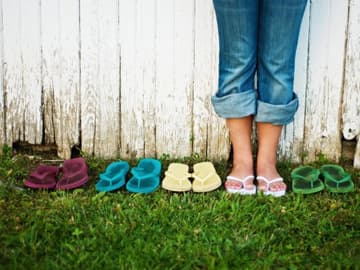 Flip-Flops Verschiedenfarbige Flip-Flops stehen um eine Frau herum.