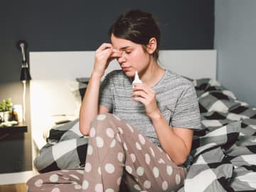 Nasenspray Frau mit Nasenspray im Bett