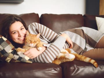 Katze_Kuscheln Frau mit Katze kuschelt auf dem Sofa