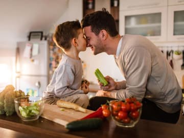 Vater_Sohn_gesund_essen Vater und Sohn in Küche essen Gemüse