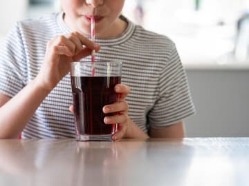 Kaltes_Getränk_Hirnfrost Kind trinkt mit Strohhalm aus Glas