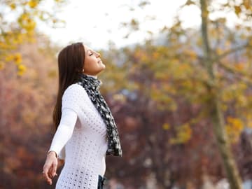Frau_atmet_draußen_Herbst Frau im Herbst atmet tief ein