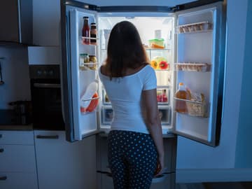 Frau_steht_vor_Kühlschrank Frau steht abends vor dem Kühlschrank