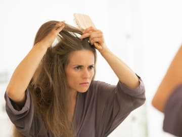 Frau_Haarekämmen_Spiegel Frau vor dem Spiegel kämmt sich die Haare