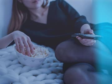 Frau-TV-Popcorn Frau guckt TV mit Popcorn
